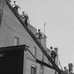 A team of Firefighters with Hoses on Their backs climbs a ladder - Art Print