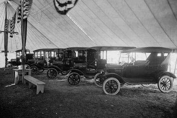 Automobiles on Display in Tent Under American Flag Banners #2 - Art Print