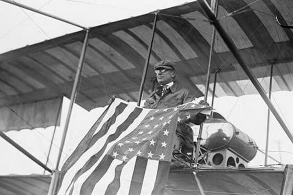 Aviator C.B. Harmon Unfurls Stars and Stripes from his pilot seat on his Biplane. - Art Print