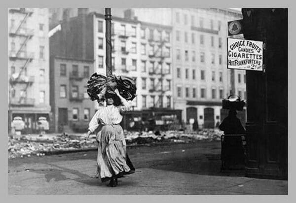 Immigrant Woman Walks Down Street Carrying a Pile of Clothing on Her Head - Art Print