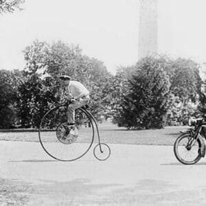 Motorcycle cop chases a Penny Farthing Velocipede down a DC Street with Washington Monument in background - Art Print