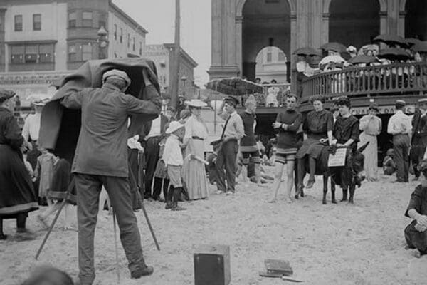 Photographer taking picture of group with donkey at crowded beach