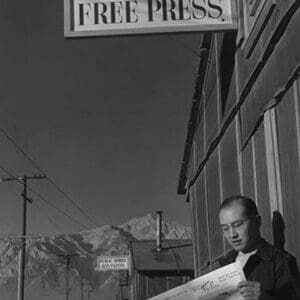 Roy Takeno Reading Paper in Front of Office by Ansel Adams - Art Print