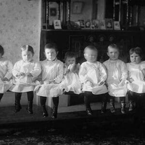 Seven Toddlers in white Dresses seated on Bench - Art Print