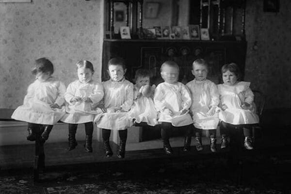 Seven Toddlers in white Dresses seated on Bench - Art Print