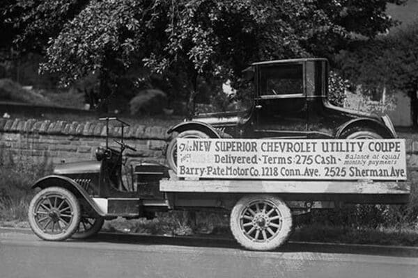 Truck carries a Chevrolet Coupe Advertisement with an actual vehicle on board - Art Print