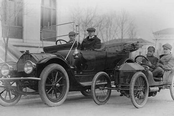 Two men in a large auto are side by two men in a Miniature Auto - Art Print